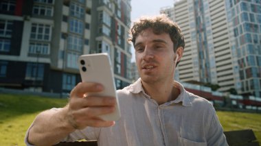 Kafkasyalı adam cep telefonu akıllı telefonu kullanıyor online toplantı kulaklık sallıyor erkek iş adamı blogcu iletişimi videolu görüşme iş ortaklığı açık hava vlogger