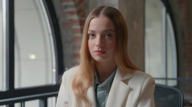 Kafkasyalı kendine güvenen iş kadını ofis içinde uzman ajan müdürü resmi sakin ciddi iş kadını kurumsal işyerinde çalışan kameraman bayan kıza bakıyor.