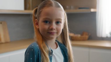 Ev mutfağında portre gülümseyen küçük mutlu bebek, çocuk evlat ediniyor. Kameraya bakıyor, güzel çocuklar gülümsüyor, çocukluk çağında evde çocuklar için sağlık sigortası yaptırıyor.