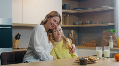 Mutfakta beyaz bir aile var. Evlatlık, mutlu, küçük bir kız çocuğu. Anne ve bebek bakıcısı.