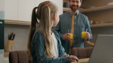 Mutfakta gülümseyen beyaz bir aile, dizüstü bilgisayarla çalışan küçük bir kız çocuğu bilgisayar oyunu oynayan bir baba, yanında likör suyu olan iki bardak getiriyor.