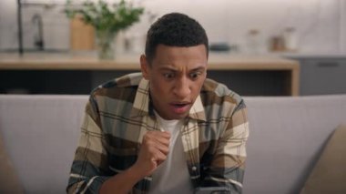 Üzücü hayal kırıklığına uğramış Afrikalı Amerikalı erkek adam internet bahislerinde başarısız oldu kumarhane evde para kaybetti cep telefonuyla ilgili kötü haberler okuyor akıllı telefon rahatsız edici mutsuz uygulama hatası