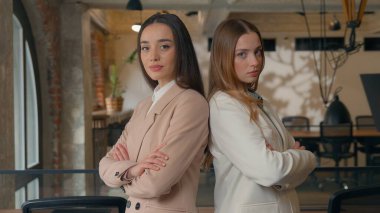 İki kendine güvenen Kafkasyalı iş kadını kızlar girişimciler kadın iş kadınları ofiste poz veren şirket çalışanları kamera ekibi çalışmalarına bakarak el ele tutuşuyorlar.