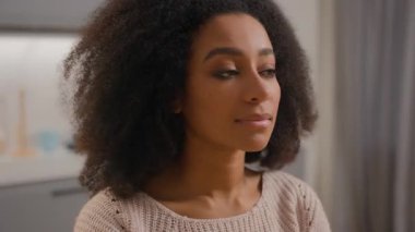 Gülümseyen, gülümseyen, Afro-Amerikan kadın, etnik kız, neşe içinde gülümseyen, mutlu ev sahibi, mutlu, mutlu, sağlıklı bayan, ev mutfağına bakan kameraya bakıyor.