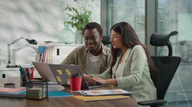 İki çok ırklı iş adamı büroda laptopla çalışan gayri resmi takım, Afrikalı Amerikalı iş adamı Hindu iş kadını arayan bilgisayar gözlemcisi erkek danışman kadın stajyer asistana yardım ediyor.