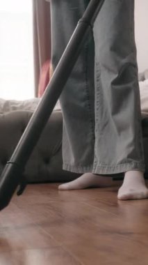 Elektrikli süpürge kadın bacaklarını kapat yatak odasının zeminini temizle tanınmaz halde kadın ev işleri yapıyor modern süpürgeyle ev hanımı ev temizliği yapıyor düzenli apartman temizliği yapıyor.