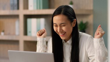 Çok şaşıran Asyalı iş kadını kadın Koreli etnik iş kadını ofis çalışanı dizüstü bilgisayarı görünce şaşırdı ve şaşırdı.