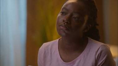 Üzgün, düşünceli, düşünceli, Afrikalı, Amerikalı, etnik kadın kız. Uyutma aleti bağımlılığı ruhsal bunalımından önce cep telefonuyla sosyal medyayı karıştırıyor.