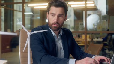 Çökmüş Kafkasyalı işadamı ofisi mühendisi rüzgar türbini modeli eko girişimi arıyor sürdürülebilirlik sorunlarıyla uğraşıyor yeşil enerji projesi dizüstü bilgisayarı düşünme planı yenilik ortamı