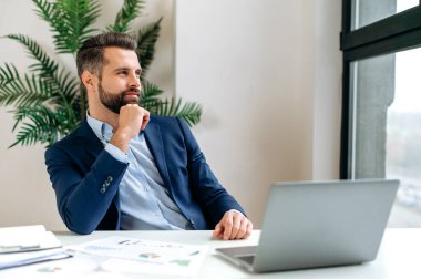 Dalgın, hayalperest, beyaz tenli başarılı iş adamı, çalışma masasında oturuyor, işe ara veriyor, pencereden dışarı bakıyor, tatilin hayalini kuruyor, yeni bir proje düşünüyor, strateji planlıyor.