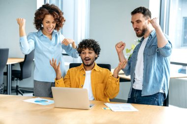Farklı uluslardan neşeli insanlar, yaratıcı iş adamları, modern bir ofiste bir projede birlikte çalışıyorlar, dizüstü bilgisayar izliyorlar, başarıyla, iyi anlaşmayla, kârla eğleniyorlar. Başarı, kazanç