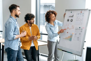 Aynı şirkette çalışan başarılı, zeki motive olmuş çok ırklı meslektaşlardan oluşan bir ekip, elinde finansal çizelgelerle ofiste duruyor ve bir projenin kavramını ve stratejisini analiz ediyor.