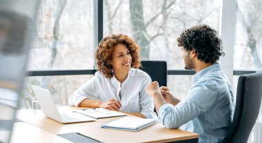 Şirketin iki dost canlısı arkadaşının panoramik fotoğrafı, Afrikalı Amerikalı kadın ve Hintli adam, modern ofiste yeni bir proje üzerinde birlikte çalışıyorlar, fikirleri ve hedefleri tartışıyorlar,
