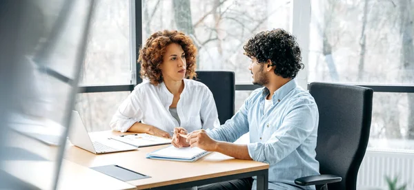 Farklı uluslardan iki çalışanın panoramik fotoğrafı modern bir ofiste yeni bir proje üzerinde birlikte çalışıyor, fikirleri ve hedefleri tartışıyor, iletişim kuruyor.