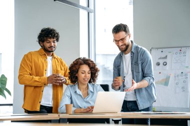 Modern ofisteki bir projede birlikte çalışan başarılı çok ırklı iş adamlarından oluşan yaratıcı bir grup, dizüstü bilgisayar kullanıyorlar, fikirleri tartışıyorlar, beyin fırtınası yapıyorlar, birbirleriyle iletişim kuruyorlar, gülümsüyorlar.