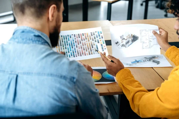 Tasarım projesi. Pantone renk paleti ve yaratıcı tasarımcıların omuzlarının üstünden evin düzeni, renkleri seçiyorlar, bir düzen geliştirmeye çalışıyorlar, fikirleri tartışıyorlar.
