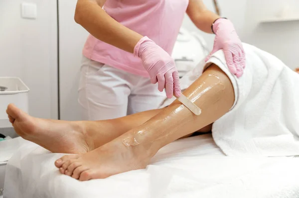 Hair removal cosmetology procedure. Aesthetic cosmetology. Laser epilation and cosmetology. Cosmetologist prepares leg before laser hair removal, applies gel on leg