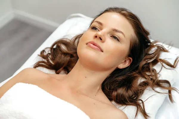 Preparation for salon procedures. Lovely calm caucasian young woman, lies on a couch in a beauty salon before body treatments or body massage, relaxes