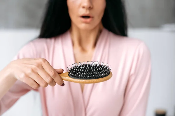 Health care, beauty treatment, hair loss problem. Close-up of a comb in female hands, with a small amount of hair falling out after combing