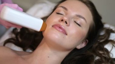 Salon prosedürleri. İstenmeyen kılları lazerle aldırma işlemi sırasında gözleri kapalı bir şekilde güzellik salonunda yatan beyaz bir kızın yüzü. Yüzünde lazer tüyü var.