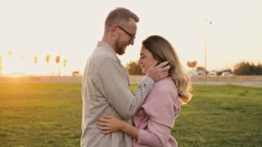 Pozitif güzel eşler. Mutlu Kafkasyalı aşık çift, gün batımında dışarıda durun, nazikçe sarılın, öpüşün, birlikte vakit geçirin, birbirinize sevgiyle bakın, gülümseyin.