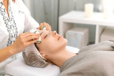 Kozmetik uzmanı, maske takmadan önce güzel beyaz bir kadının yüzünü özel disklerle temizler. Güzellik salonunda yüz bakımı prosedürleri. Güzellik konsepti