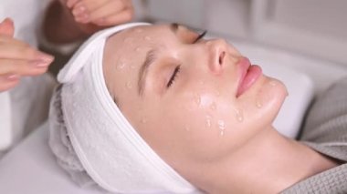 Kozmetik uzmanı, yüz derisinin kalitesini arttırmak için güzel beyaz bir kadının yüzüne özel bir jel sürüyor. Güzellik salonunda yüz bakımı prosedürleri. Güzellik tedavisi