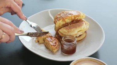 Kahvaltıda krep. Kadın kahvaltıda akçaağaç şurubuyla ya da bal ile krep kesiyor.