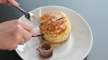 Kadın kahvaltıda akçaağaç şurubuyla ya da bal ile krep kesiyor. Kahvaltıda krep.