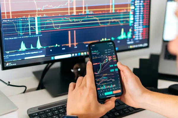 Online trading. Close-up of a smartphone in male hands, with trading data index chart graph on the screen, mobile phone app analytics for cryptocurrency market