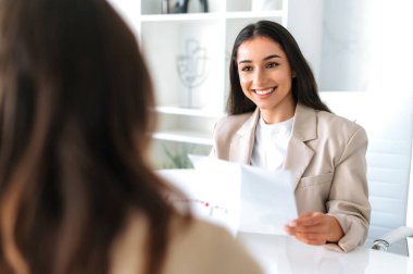 İşbirliği konsepti. Olumlu Arap ya da Hintli genç iş kadını, şirket patronu, finans CEO 'su iş ortağı ya da çalışanıyla modern ofis toplantılarında fikir ve stratejiyi tartıştı