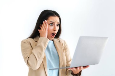 Şaşırmış Hintli ya da Arap iş kadını, ofis çalışanı, açık bir dizüstü bilgisayar tutuyor, hayal kırıklığına uğramış ağzı açık bakıyor, izole edilmiş beyaz arka planda duruyor, eliyle başını tutuyor.