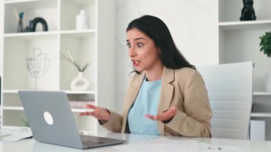 Sinirli Arap ya da Hintli iş kadını, şirket çalışanı, finans CEO 'su, ofiste işyerinde oturuyor, dizüstü bilgisayar ekranına şaşkın bakıyor, çalışanlardan kötü performans sonuçları alıyor.