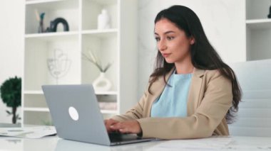 Kazanmak, başarı. Neşeli, şaşkın, mutlu Hintli ya da Arap iş kadını, modern bir ofiste oturuyor, işyerinde sevinçle terfi ediyor, büyük kazanç sağlıyor, dokümanları neşeyle fırlatıyor, eğleniyor, gülüyor, el kol hareketi yapıyor.