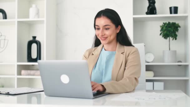 在办公室工作 快乐的印度或阿拉伯商业女性 公司员工 穿着西服 在工作中使用笔记本电脑 在工作场所做一个项目 在网上搜索信息 — 图库视频影像