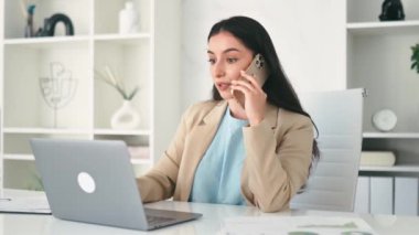 Telefon konuşması. Meşgul Hintli ya da Arap iş kadını, şirket çalışanı, CEO, ofiste çalışma masasında oturuyor, akıllı telefonla konuşuyor, ortağı ya da müşterisiyle konuşuyor, dizüstü bilgisayar kullanıyor, gülümsüyor.