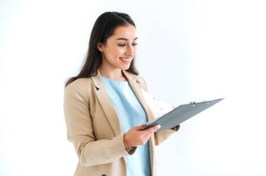 Şirin, güzel, esmer, Hintli ya da Arap iş kadını, mali danışman, sekreter, izole edilmiş beyaz arka planda duruyor, elinde dosyalar ve grafiklerle, ona bakıyor, gülümsüyor.