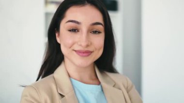 Kadın video portresi. Güzel, başarılı Hintli ya da Arap kadın, CEO, emlak komisyoncusu, şirket yöneticisi, şık bir takım elbise giymiş, modern bir ofis yerinde duruyor, kameraya gülümsüyor.