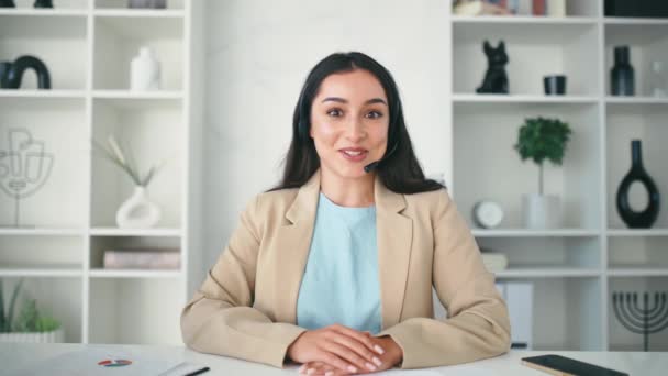 ポジティブ成功したアラビア人またはヘッドセットを持つインド人女性 女性教師 ビジネスコンサルタントは クライアントとのオンライン相談中にオフィスに座って 挨拶の対話者 — ストック動画