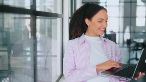 自信华丽的 成功的多种族 卷发的年轻女子 软件工程师 手握笔记本电脑 站在一个现代化的办公室里 看着相机 面带微笑地友善 — 图库视频影像
