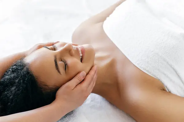Calm Relaxed Brazilian Hispanic Young Woman Lies Salon Head Massage Stock Photo