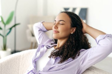 Büyüleyici, sakin, kıvırcık saçlı, stil sahibi bir kadın. İnternetteki işine ara veriyor. Ellerini başının arkasına koyup gözlerini kapatıyor.