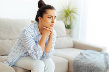 Kızgınlık, depresyon, stres. Üzgün Arap ya da Hintli genç bir kadın, oturma odasında bir kanepede oturur, üzgün, yorgun ve yalnız hisseder, depresyon geçirir, kişisel sorunlardan ya da boşanmadan endişelenir.