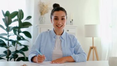 Çekici, beyaz tenli, mavi gömlekli, masa başında oturan, yönetici ya da mali danışman. Bilgi yazıyor, sunum hazırlıyor, kameraya bakıyor, gülümsüyor.