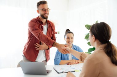 Başarılı bir anlaşma. Meslektaşlar birbirlerine gülümserken el sıkışıyorlar. Bir grup iş ortağı modern bir ofiste birlikte çalışıyorlar, iyi bir anlaşma yapıyorlar, işbirliğini planlıyorlar.