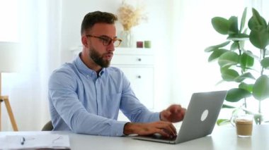 Kafası karışmış Kafkasyalı ya da Arap işadamı, modern ofiste bir masada oturup beklenmedik haberler okurken bilgisayar ekranına bakarken şaşkın bir şekilde