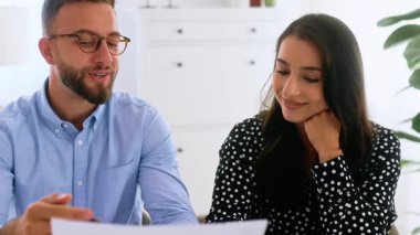 Motive edilmiş profesyonel erkek ve kadın modern bir ofis masasında iş görüşmesi yapıyorlar, finansal tabloları ve belgeleri dikkatle inceliyorlar, yeni fikirler ve stratejiler geliştiriyorlar, gülümsüyorlar.