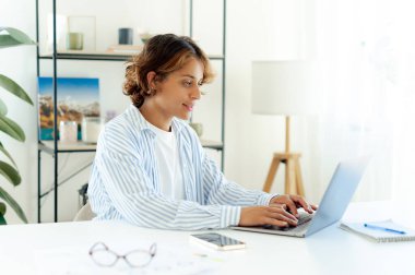 Modern ofisinde çalışırken dizüstü bilgisayarda yazı yazan oldukça Brezilyalı yaratıcı bir profesyonel. Gözlüklü genç bayan serbest yazar, dijital projeye ya da ofis ortamında iletişim kurmaya odaklanmış.