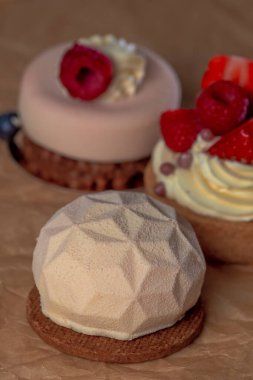 three delicious cakes with fruit on brown paper, large photo.