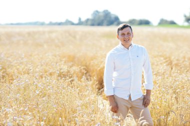 Beyaz gömlekli yakışıklı iş adamı buğday tarlasında duruyor. Açık hava çekimi. Yüksek kalite fotoğraf